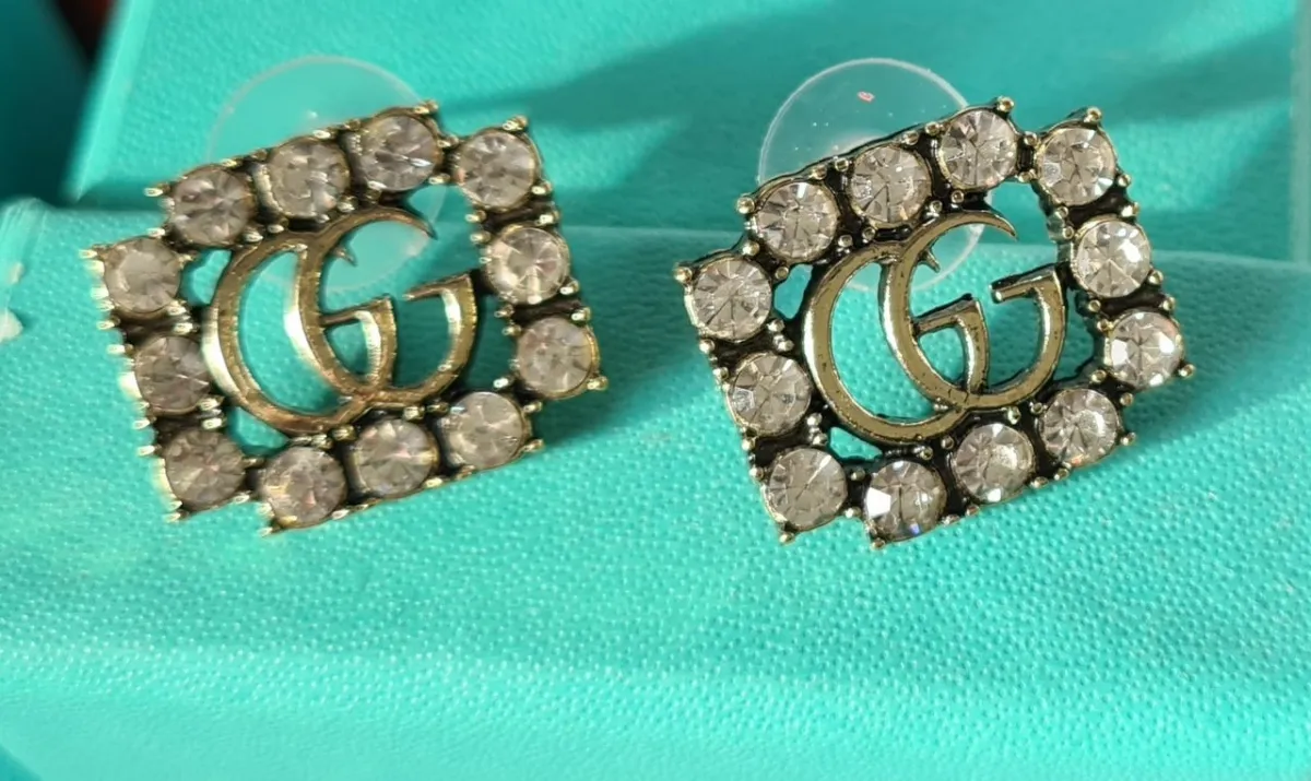 Brincos GC pequeno dourado com cristais transparente. 