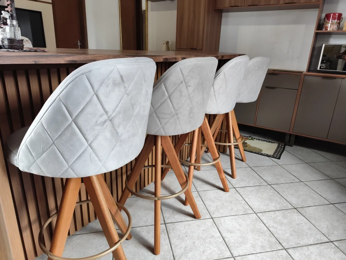 Banqueta Baixa Giratória, 63cm do chão ao assento, Modelo Redondo, Tecido Veludo Império cor Cru, Madeira cor Mel, Argola Dourado/ Champagne, Costuras interna Pétala, Matelasse nas costas. Imagem